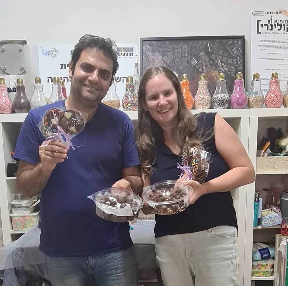 בני זוג יושבים סביב שולחן שוקולדים ומתעסקים בעבודת יד.