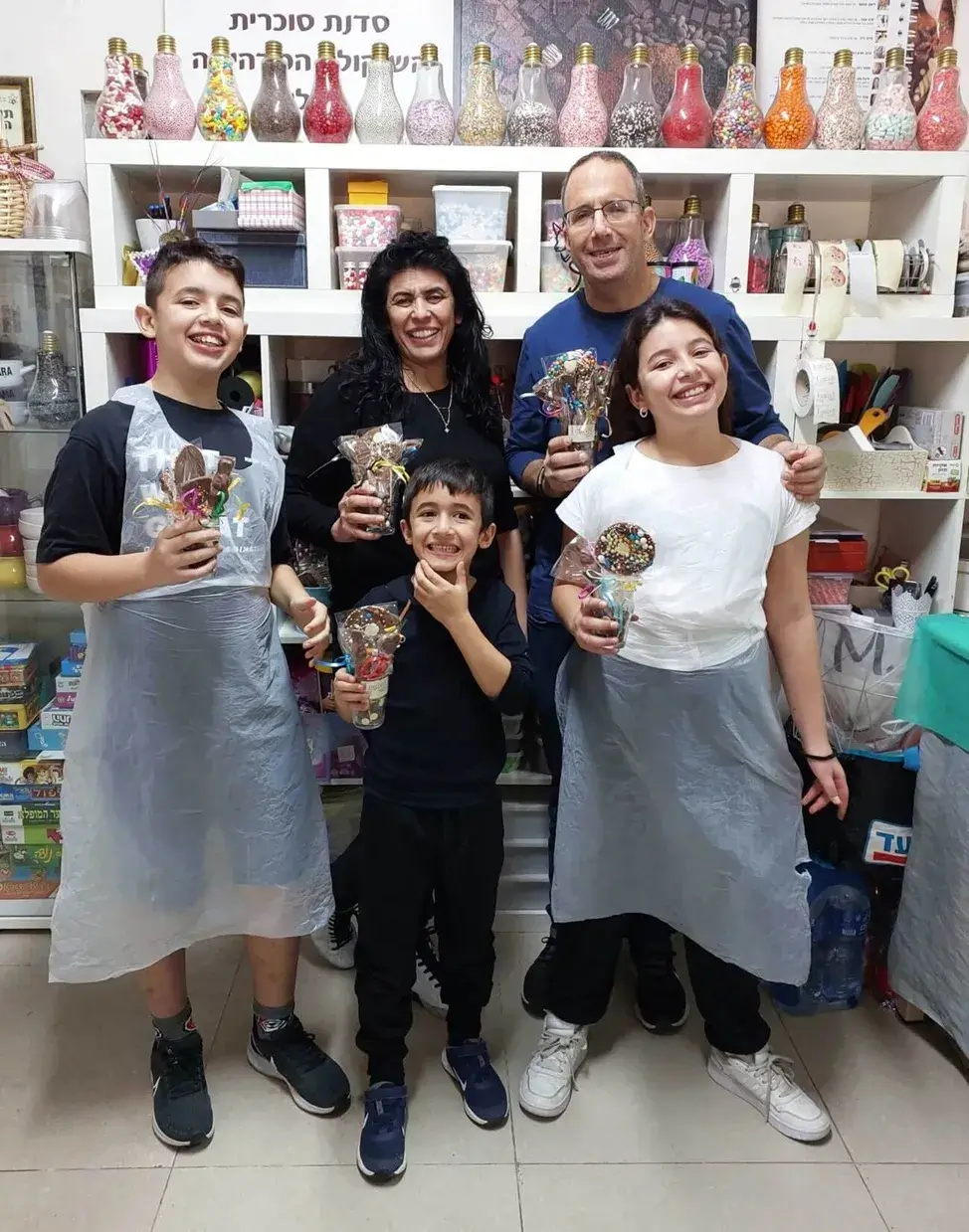 משפחות יושבות סביב שולחן בסדנת שוקולד משפחתית עם חיוכים והתרגשות