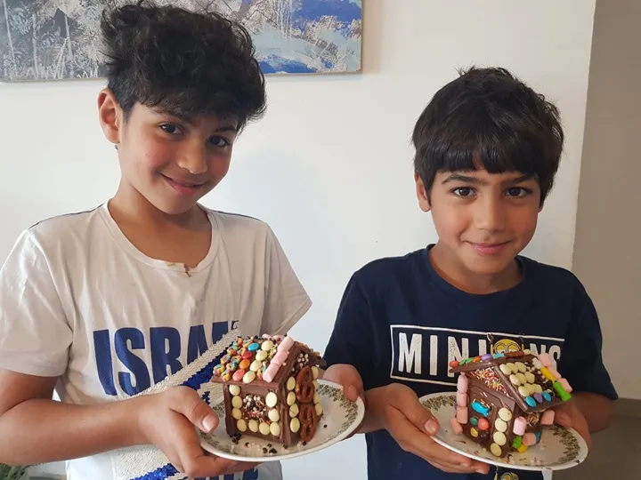ילדים מחייכים ומציגים לראווה את בית השוקולד שבנו