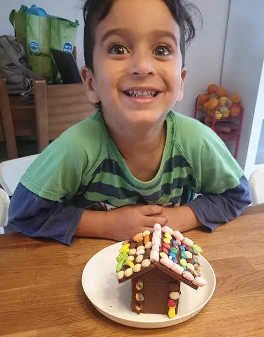ילד מחייך ומציג לראווה את בית השוקולד שבנה
