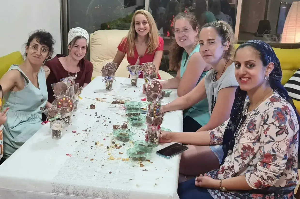 מבוגרים נהנים מהכנת פרלינים בסדנת שוקולד.