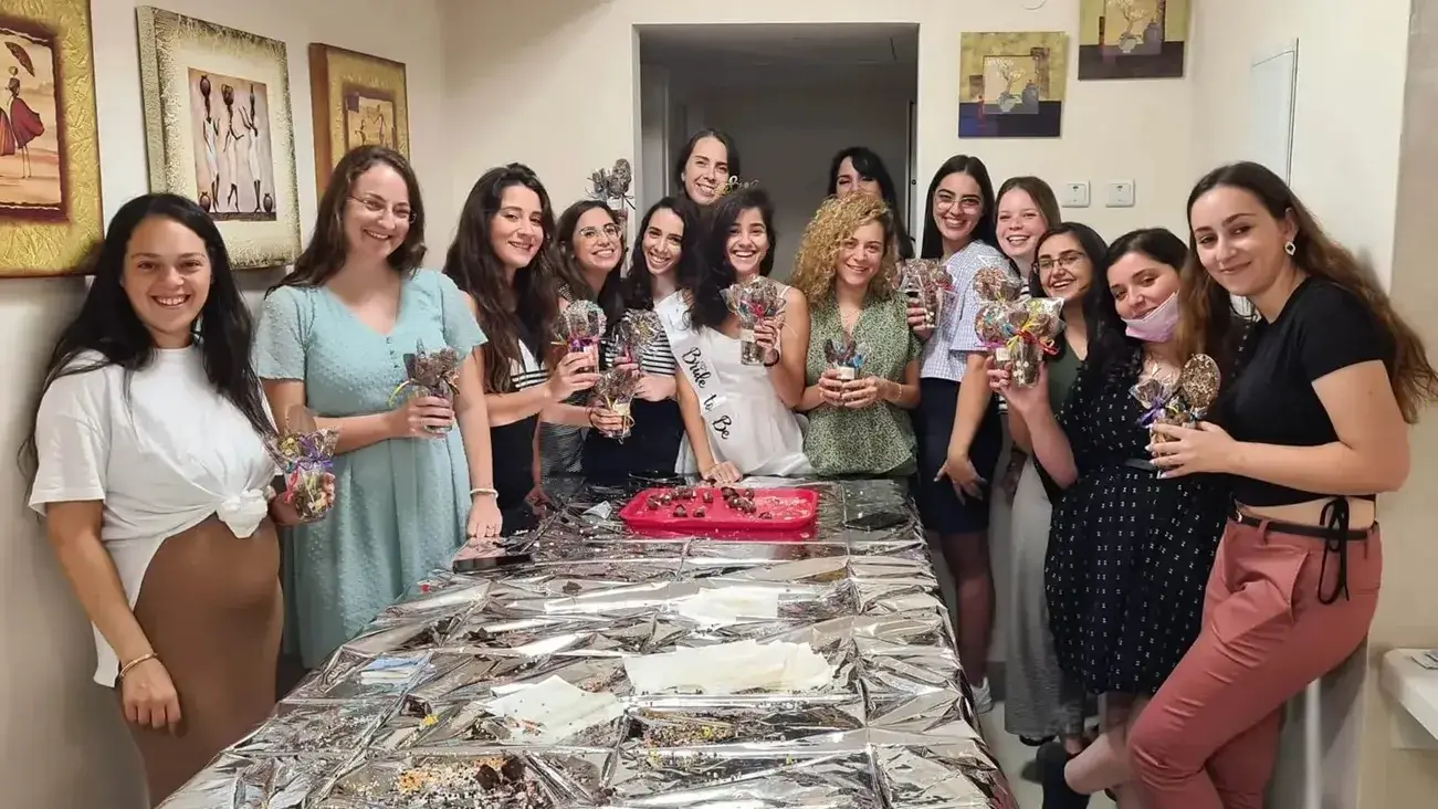 משתתפים מבוגרים משלבים טעמים שונים בשוקולד, כמו פירות יבשים ותבלינים, בסדנת שוקולד.
