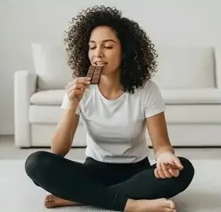 אשה יושבת ואוכלת שוקולד בנחת וברוגע